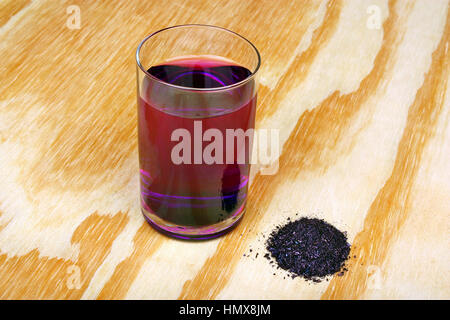 Amas de cristaux de permanganate de potassium et l'eau d'un verre sur une table en bois Banque D'Images