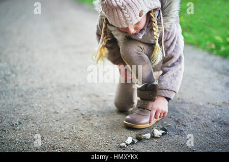 Petit enfant pointe sur des pierres sur la route. Tourné en extérieur horizontal Banque D'Images