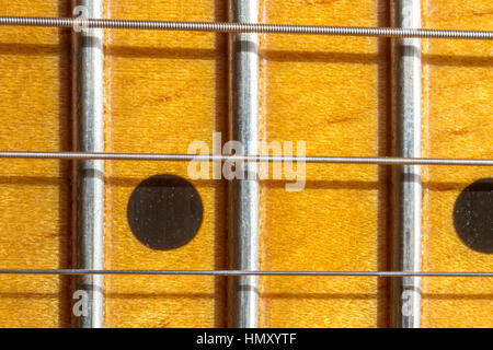 Gros plan d'une planche de fret d'érable de guitare électrique et des cordes montrant les frettes d'acier, les cordes et les incrustations de marqueur de point Banque D'Images