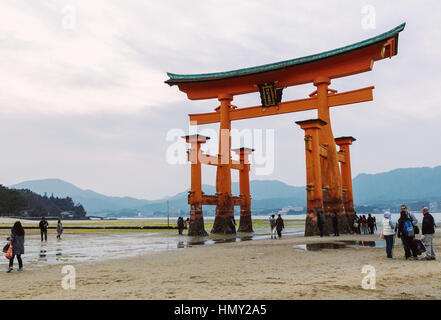 Les gens apprécient l'immense torii flottant du sanctuaire d'Itsukushima à marée basse le soir dans l'île de Miyajima, J Banque D'Images