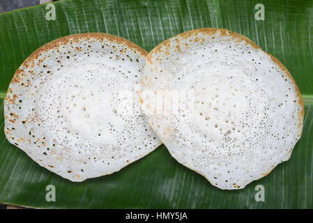 Appam avec mouton rôti de viande de boeuf//curry vert en feuille de bananier. faites de farine de riz traditionnelles populaires nourriture du petit déjeuner au Kerala Banque D'Images