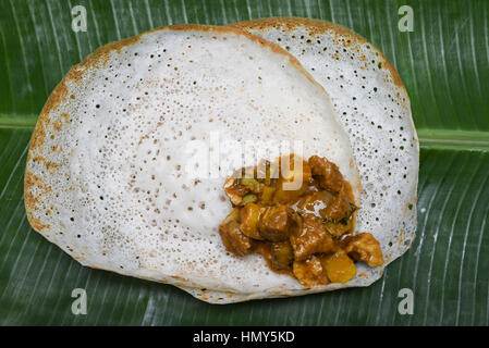 Appam avec mouton rôti de viande de boeuf//curry vert en feuille de bananier. faites de farine de riz traditionnelles populaires nourriture du petit déjeuner au Kerala Banque D'Images