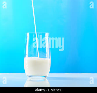 Verser le lait en verre isolé sur fond bleu Banque D'Images