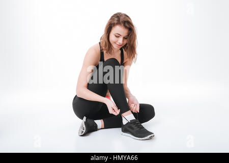 Photo de jolie jeune femme assise fitness isolated over white background et cravate laces Banque D'Images