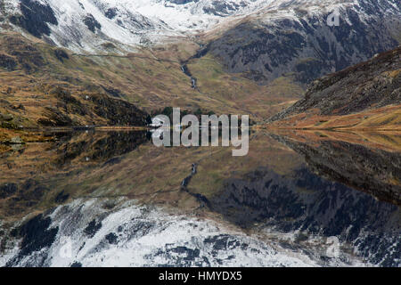 Vue vers l'ouest le long de Llyn Ogwen dans le parc national de Snowdonia dans le Nord du Pays de Galles. Les pics couverts de neige de Snowdonia en arrière-plan. Banque D'Images