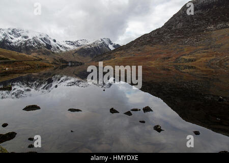 Vue vers l'ouest le long de Llyn Ogwen dans le parc national de Snowdonia dans le Nord du Pays de Galles. Les pics couverts de neige de Snowdonia en arrière-plan. Banque D'Images