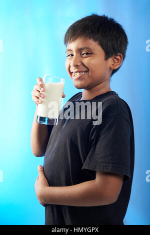 Chubby boy smiling avec verre de lait isolé sur blue Banque D'Images