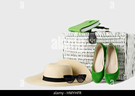 Valise en osier blanc, womens chapeau, lunettes, chaussures vert et le bloc-notes. Focus sélectif. Banque D'Images