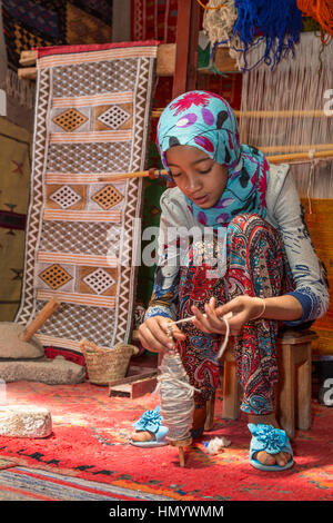 Le Maroc. Jeune fille berbère Amazigh travaillent avec la laine sur une fusée. Ksar Ait Benhaddou, un site du patrimoine mondial. Banque D'Images