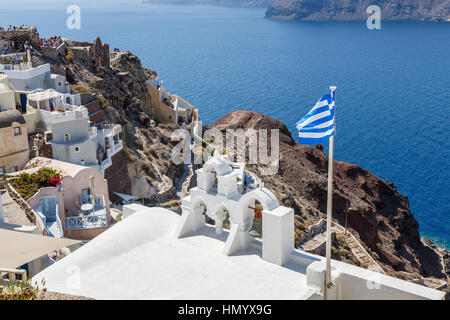 Drapeau grec battant par le clocher d'une église orthodoxe grecque blanchis à Oia, Santorini, une île grecque de la Méditerranée dans le groupe des Cyclades Banque D'Images