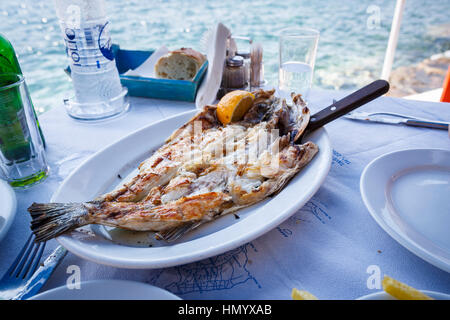 Délicieux poisson frais grillé servi sur une table à la taverne en bord de mer dans la baie d'Ammoudi, Oia, Santorin, une île grecque de la Méditerranée dans les Cyclades grou Banque D'Images