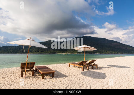 Idyllique plage de sable blanc avec chaises longues et parasol à Koh Lipe Island dans le sud de la Thaïlande dans la mer d'Andaman. Une longue queue traditionnels voiles baot en t Banque D'Images