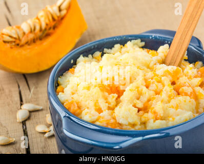 Porridge de millet avec citrouille dans bol bleu, la citrouille et les graines de citrouille sur une table en bois libre Banque D'Images