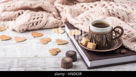 Tasse de café sur un ordinateur portable avec écharpe en tricot beige , bougies et beaucoup de coeurs en bois couché sur un tableau blanc Banque D'Images