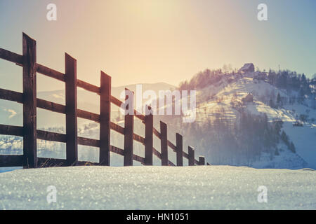 Une campagne magnifique paysage avec clôture en bois et le lever du soleil la lumière sur les collines et les vallées couvertes de neige au col Rucar-Bran, Roumanie. Focus sélectif. Banque D'Images