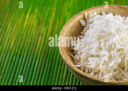 Flocons de noix de coco déshydratée dans bol en bois. Banque D'Images