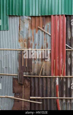 Un mur composé de feuilles impaires de feuilles de fer ondulé de couleur rouille. Kompong Cham, Cambodge Banque D'Images