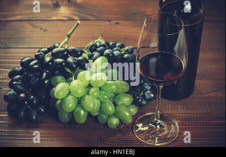 Bouteille et verre de vin rouge et de raisin sur fond de bois Banque D'Images