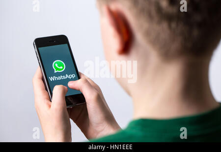 Un adolescent en utilisant WhatsApp sur un téléphone mobile Banque D'Images