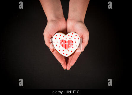 Beau coeur d'épices dans les mains de la jeune fille sur un fond noir. Carte postale pour la Saint-Valentin, le 8 mars, jour de la Fête des mères ou un mariage. Espace libre Banque D'Images