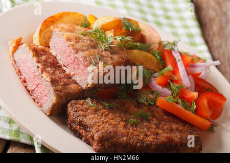 Ronde pané steak avec pommes de terre et les légumes sur une plaque horizontale. Banque D'Images