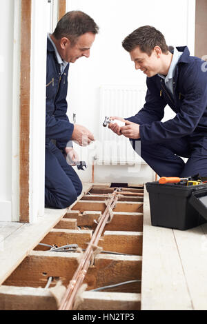 Apprenti plombier et installation du chauffage central dans la chambre Banque D'Images