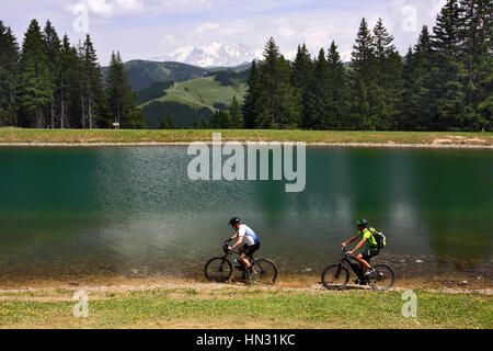Deux cyclistes de montagne équitation le long du lac avec le Mont Blanc en arrière-plan, les Alpes, France Banque D'Images
