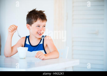 Portrait of smiling little boy refuse de manger de délicieux yaourts Banque D'Images