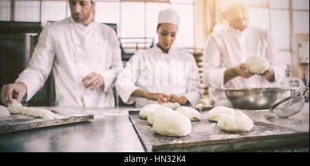 Collègues sérieux pâte non cuite de pétrissage dans la cuisine de la boulangerie Banque D'Images