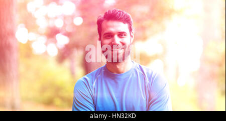 Portrait of smiling man standing in forest with arms crossed Banque D'Images