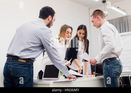 Les jeunes gens d'affaires au cours de réunions et l'examen avec la paperasserie et les ordinateurs portables. Banque D'Images