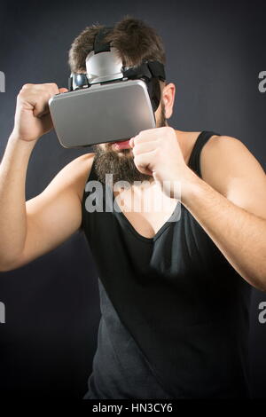 Homme barbu avec des lunettes VR en garde de boxe permanent Banque D'Images