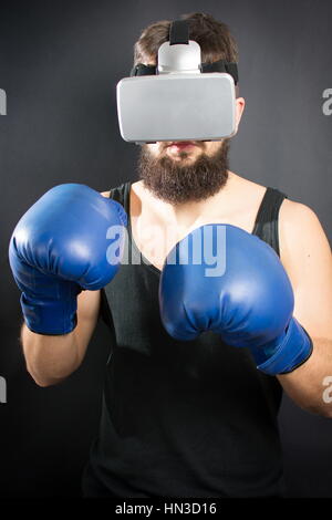 Homme barbu avec des lunettes VR en garde de boxe permanent Banque D'Images