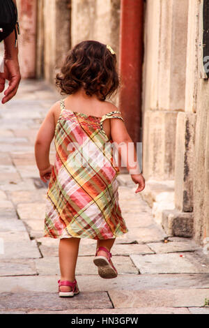 Jeune enfant en marchant sur un trottoir de la rue pavée Banque D'Images