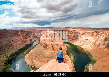 Jeune homme assis sur un rocher à Horseshoe Bend, coude de la rivière Colorado, King Bend, Glen Canyon National Recreation Area, Page Banque D'Images