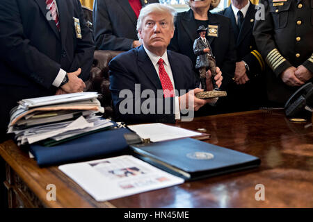 Le Président américain Donald Trump soutient une statue qu'il a reçu en cadeau lors de sa rencontre avec county sheriffs dans le bureau ovale de la Maison Blanche à Washington, DC, États-Unis, le mardi, 7 février 2017. L'administration d'Atout sera de retour en cour mardi pour faire valoir qu'il a une grande autorité sur la sécurité nationale et d'exiger le rétablissement d'une interdiction de voyager à sept pays à majorité musulmane que les réfugiés en détresse, a déclenché des protestations et remis le jeune gouvernement son premier test crucial. Crédit : Andrew Harrer/Piscine via CNP - PAS DE SERVICE DE FIL- Photo : Andrew Harrer/consolidé/Piscine/dpa Banque D'Images