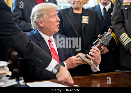 Le Président américain Donald Trump ressemble à une statue qu'il a reçu en cadeau lors de sa rencontre avec county sheriffs dans le bureau ovale de la Maison Blanche à Washington, DC, États-Unis, le mardi, 7 février 2017. L'administration d'Atout sera de retour en cour mardi pour faire valoir qu'il a une grande autorité sur la sécurité nationale et d'exiger le rétablissement d'une interdiction de voyager à sept pays à majorité musulmane que les réfugiés en détresse, a déclenché des protestations et remis le jeune gouvernement son premier test crucial. Crédit : Andrew Harrer/Piscine via CNP - PAS DE SERVICE DE FIL- Photo : Andrew Harrer/consolidé/Piscine/dpa Banque D'Images