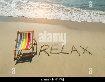 Chaise relax avec écrit dans le sable écrire on tropical beach. Banque D'Images