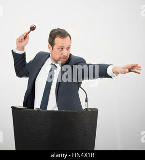 Un commissaire-priseur mâle en action holing a gavel au cours d'une vente aux enchères. Banque D'Images