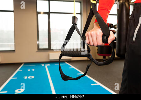 Les mains des hommes avec des sangles TRX fitness dans une salle de sport. Banque D'Images