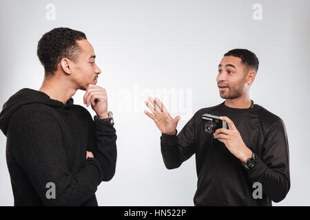 Photo de deux jeunes hommes africains-américains debout sur fond blanc. Un homme tenir l'appareil photo. Banque D'Images