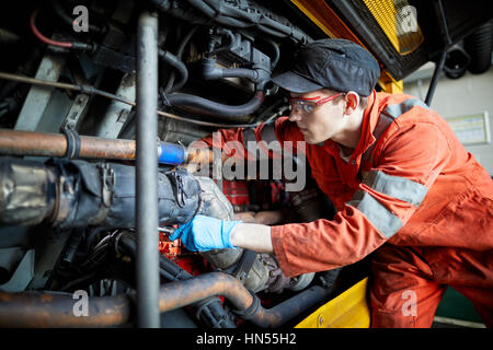 Un jeune apprenti mécanicien monteur d'adolescent ventilé fixation moteur au bus à impériale bus Stagecoach opérateurs Wythenshawe depot à Manchester, en Banque D'Images