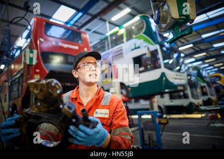 Un jeune apprenti mécanicien monteur d'adolescent ventilé fixation moteur au bus à impériale bus Stagecoach opérateurs Wythenshawe depot à Manchester, Banque D'Images