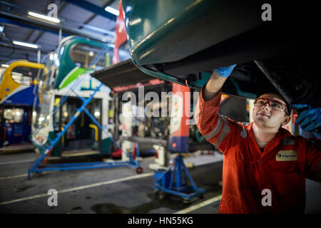 Un jeune apprenti mécanicien monteur d'adolescent ventilé fixation moteur au bus à impériale bus Stagecoach opérateurs Wythenshawe depot à Manchester, Banque D'Images