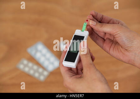 Close-up of woman mains avec du sucre de sang test diabete contre fond de bois Banque D'Images
