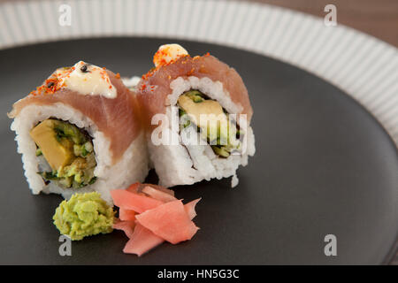 Close-up of sushi uramaki servi en noir sur plaque ronde table en bois Banque D'Images