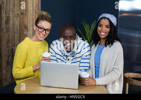 Portrait of happy friends using laptop while having coffee in cafÃƒÂ© Banque D'Images