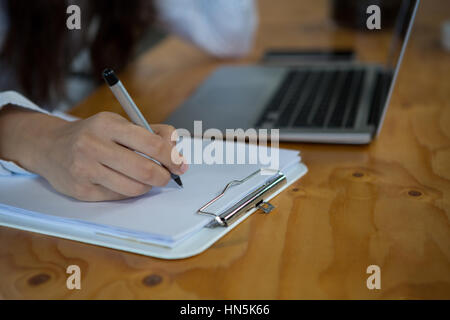 Close-up of business executive writing on clipboard Banque D'Images