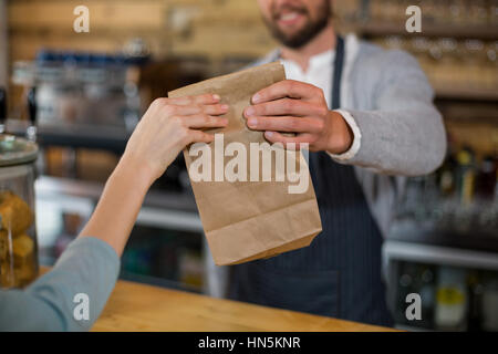 Woman receiving colis provenant de serveur au comptoir de cafe Banque D'Images