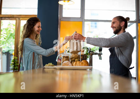 Woman receiving colis provenant de serveur au comptoir de cafe Banque D'Images